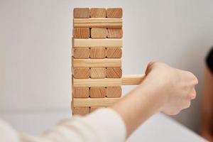 famiglia giocare tavola gioco. mani prendere di legno bloccare a partire dal Torre. foto