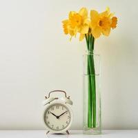 allarme orologio e fiori nel vaso su bianca sfondo foto