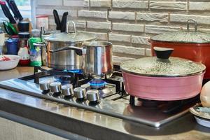 cucinando cibo nel frittura padella e pentola su gas stufa nel il cucina. casa cucinando concetto foto