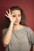 ritratto di emotivo positivo europeo adolescenziale ragazza indossare sua leggero capelli nel panino, urlando nel stupore o stupore conservazione mani su viso foto