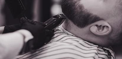 il barbiere taglia la barba a un uomo foto
