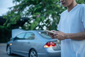 sicurezza di emergenza. l'uomo sta componendo un telefono cellulare per un numero di emergenza a causa di un guasto a un'auto nella foresta. la manutenzione dell'auto prima del viaggio aumenta la sicurezza dagli incidenti. foto