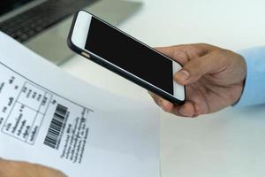 attività commerciale uomo uso Telefono per scansione codice a barre o qr codici per pagare credito carta conto dopo ricevente documento fattura in linea. pagami foto