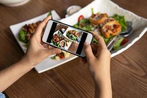 donna prendere immagine di un' pasto su il tavolo dopo ordinazione cibo in linea per mangiare a casa. fotografia e uso Telefono concetti foto