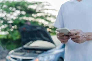 sicurezza di emergenza. l'uomo sta componendo un telefono cellulare per un numero di emergenza a causa di un guasto a un'auto nella foresta. la manutenzione dell'auto prima del viaggio aumenta la sicurezza dagli incidenti. foto