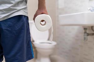 uomo in piedi nel bagno Tenere tessuti con acuto stomaco dolore. stomaco crampi, addominale dolore, diarrea, colon o pancia cancro foto