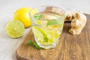 soda allo zenzero biologico in un bicchiere con limone e lime foto