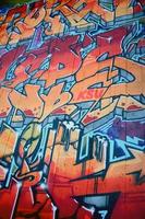 un' frammento di dettagliato graffiti di un' disegno fatto con aerosol vernici su un' parete di calcestruzzo piastrelle. sfondo Immagine di strada arte nel caldo rosso colore toni foto