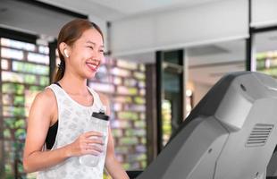 giovane contento asiatico donna atleta correre su tapis roulant, in esecuzione macchina, nel interno Palestra fitness per Salute foto