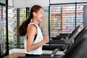 giovane contento asiatico donna atleta correre su tapis roulant, in esecuzione macchina, nel interno Palestra fitness per Salute foto