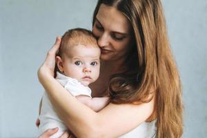 ritratto di giovane donna mamma con lungo capelli Tenere bambino ragazza su mani a il casa foto