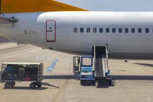 Caricamento in corso - scarico borse, bagaglio e per o a partire dal un aereo nel il aeroporto. carico su veicolo aspetta per trasporto per aereo. foto