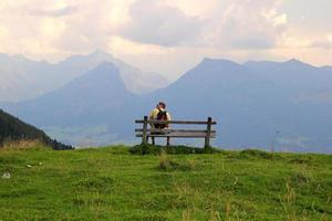 viaggio per sankt-wolfgang, Austria. il giovane uomo siamo seduta su un' panchina con Visualizza su il montagne. foto