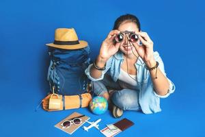 giovane viaggiatore asiatico donna felice in camicia blu con zaino con e attrezzatura per le vacanze dei viaggiatori con una mappa, su sfondo di colore blu. zaino da viaggio foto