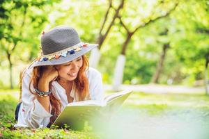 natura di viaggio donna asiatica. viaggiare rilassati. dormire leggendo il libro sul prato del parco. in estate. foto