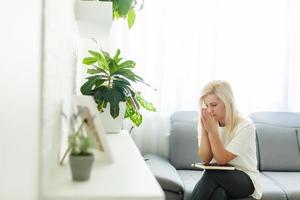 ragazza pregando. lato Visualizza di bellissimo giovane biondo capelli donna preghiere a casa foto