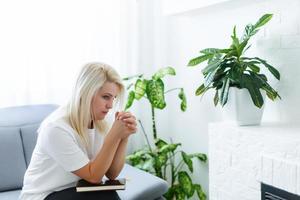 ragazza pregando. lato Visualizza di bellissimo giovane biondo capelli donna preghiere a casa foto