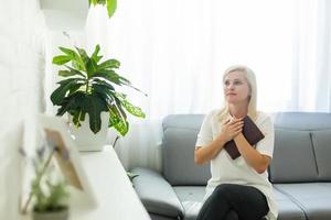 ragazza pregando. lato Visualizza di bellissimo giovane biondo capelli donna preghiere a casa foto