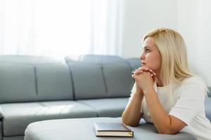 ragazza pregando. lato Visualizza di bellissimo giovane biondo capelli donna preghiere a casa foto