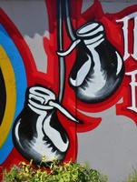 il vecchio parete, dipinto nel colore graffiti disegno con aerosol vernici. il Immagine di rosso boxe guanti sospeso su il parete foto
