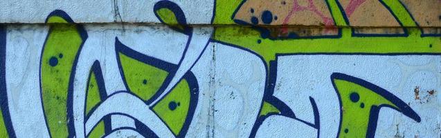 frammento di graffiti disegni. il vecchio parete decorato con dipingere macchie nel il stile di strada arte cultura. colorato sfondo struttura nel verde toni foto