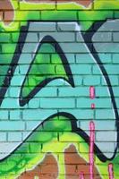 frammento di graffiti disegni. il vecchio parete decorato con dipingere macchie nel il stile di strada arte cultura. colorato sfondo struttura nel verde toni foto