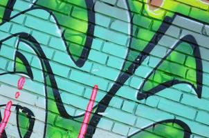 frammento di graffiti disegni. il vecchio parete decorato con dipingere macchie nel il stile di strada arte cultura. colorato sfondo struttura nel verde toni foto