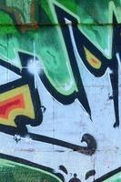 frammento di graffiti disegni. il vecchio parete decorato con dipingere macchie nel il stile di strada arte cultura. colorato sfondo struttura nel verde toni foto