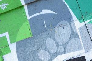 frammento di graffiti disegni. il vecchio parete decorato con dipingere macchie nel il stile di strada arte cultura. colorato sfondo struttura nel verde toni foto