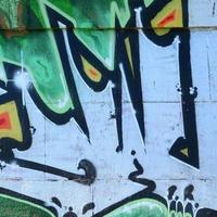 frammento di graffiti disegni. il vecchio parete decorato con dipingere macchie nel il stile di strada arte cultura. colorato sfondo struttura nel verde toni foto