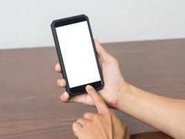 uomo hold mobile Telefono vuoto bianca schermo modello su il tavolo foto