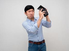 uomo d'affari blu camicia si sente scoraggiato di trova i soldi nel il suo portafoglio, povero asiatico uomo no i soldi isolato foto