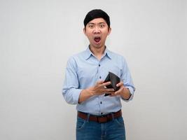 asiatico uomo blu camicia si sente scioccato a viso Tenere vuoto portafoglio no i soldi isolato foto