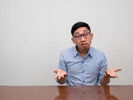 asiatico uomo d'affari indossare bicchieri sedersi a tavolo gesto confuso e dubbio foto