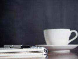 avvicinamento taccuino con penna e bianca caffè tazza sfondo foto