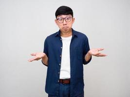 giovane asiatico uomo indossare bicchieri gesto confuso mostrare mani su isolato foto