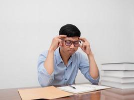 asiatico uomo d'affari indossare bicchieri sedersi a Lavorando tavolo hold il suo testa si sente provato foto