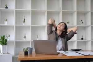 asiatico donna d'affari tratti sua braccia per rilassare sua stanco muscoli a partire dal Lavorando a sua scrivania tutti giorno a il ufficio. foto