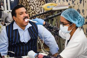 delhi, India - novembre 19, 2022 - vicino su di femmina dentista fare routine dentale verifica per paziente, paziente dire bugie su sedia a annuale Salute verifica, dentista fare dentale verifica per paziente foto