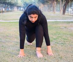 giovane indiano donna praticante yoga all'aperto nel un' parco. bellissimo ragazza pratica di base yoga posa. quiete e relax, femmina felicità. di base yoga pose all'aperto foto
