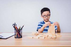 ragazzo asiatico che gioca con un puzzle di legno foto