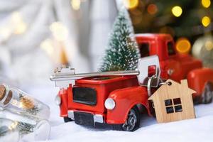 rosso retrò auto con un' Natale albero decora con il Casa chiave nel il Raccogliere camion per Natale. acquisto un' casa, in movimento, mutuo, prestito, vero proprietà, festivo umore, nuovo anno foto