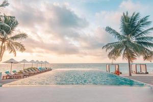 ombrello e sedia in giro infinito nuoto piscina vicino mare oceano spiaggia a Alba o tramonto volta. per tempo libero viaggio e vacanza concetto, estate ricorrere paesaggio. tropicale rilassamento vacanza, tramonto foto