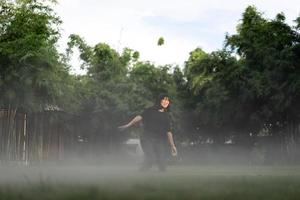 asiatico corto capelli donna è gioioso salto nel il nebbia ambiente su erba campo giardino. foto