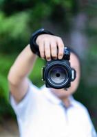 asiatico uomo detiene il medio formato telecamera nel il suo mano e messa a fuoco per sparare nel davanti di lui. foto