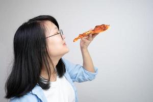 contento bicchieri asiatico giovane donna mangiare Pizza su bianca sfondo. foto
