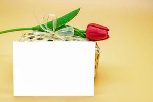 vuoto carta nel davanti di merenda pacchetto e artefatto rosso tulipano su superiore di esso su il crema - arancia sfondo. foto