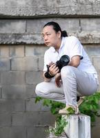 asiatico professionale cineoperatore si siede e pensa di Come per creare un' creatività foto nel il costruzione la zona sfondo e ambiente.