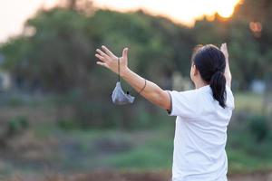 asiatico uomo prendere via maschera e salire il suo mano su nel d'oro crepuscolo volta. foto