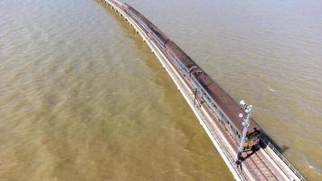 aereo Visualizza di un sorprendente viaggio treno parcheggiata su un' galleggiante ferrovia ponte al di sopra di il acqua di il lago nel papà sak jolasid diga con blu cielo a lopburi, Tailandia. foto